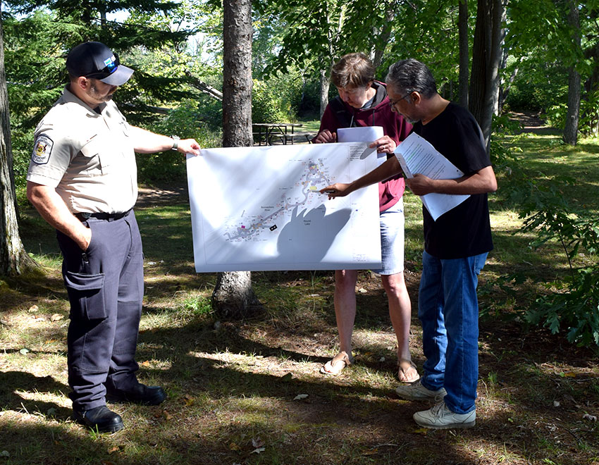 photo of jason mask, betty biesenthal and sami hasanian looking at trail plan