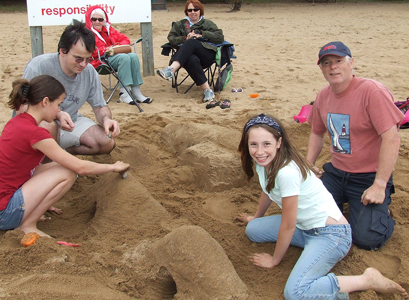 photo of family building a sand sculpture on beach at bonnechere park