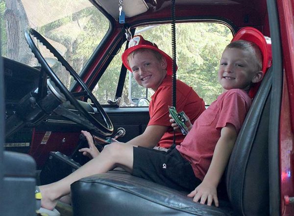 photo of two boys sitting in the cab of a fire truck