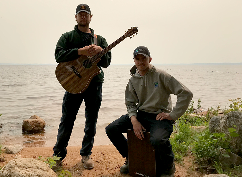photo of two park staff on beach with guitar